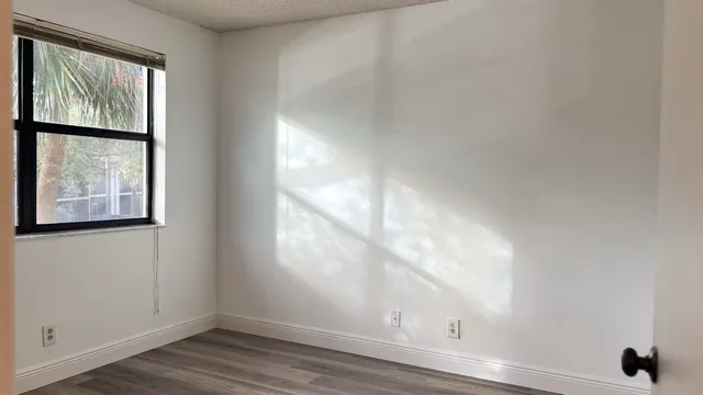 a view of an empty room with wooden floor and a window
