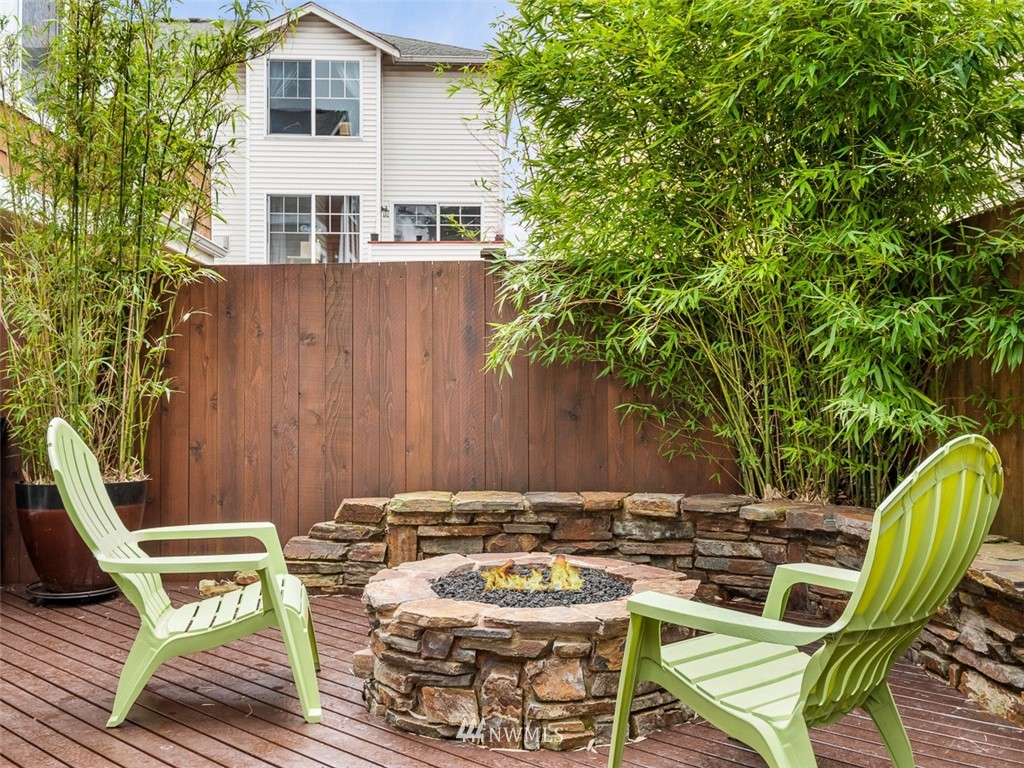 1212 North 85th Street, Unit B Seattle, WA 98103 - Photo 28 of 28 a view of a patio with table and chairs and potted plants with wooden floor and fence
