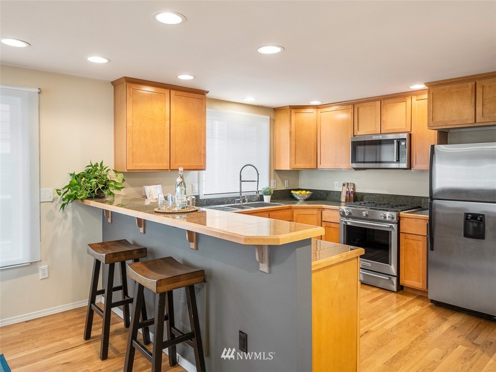 1212 North 85th Street, Unit B Seattle, WA 98103 - Photo 8 of 28 a kitchen with kitchen island granite countertop wooden cabinets and a refrigerator