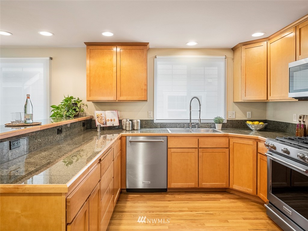 1212 North 85th Street, Unit B Seattle, WA 98103 - Photo 9 of 28 a large kitchen with stainless steel appliances granite countertop a sink a stove top oven a counter space and cabinets