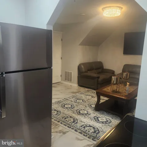 a living room with furniture and a refrigerator