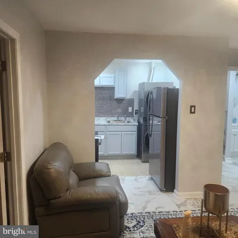 a living room with furniture and a refrigerator