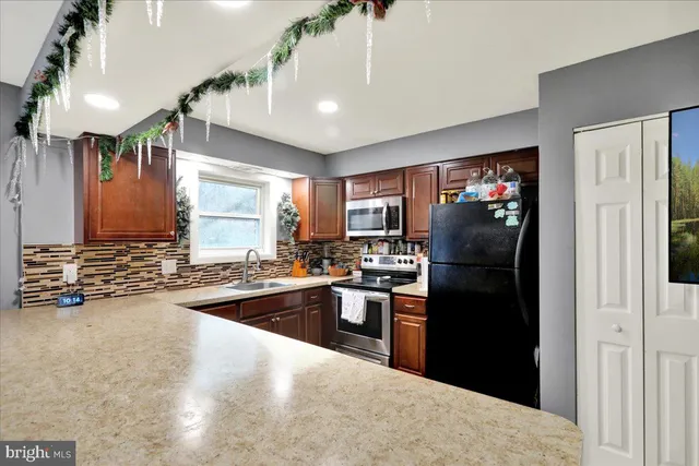 a kitchen with stainless steel appliances granite countertop a refrigerator a sink dishwasher a stove and a refrigerator with wooden floor