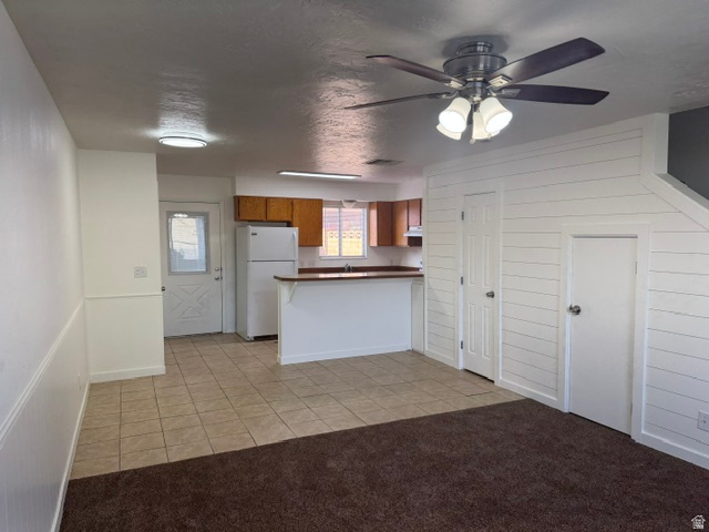 1797 West 950 North, Unit 2 St. George, UT 84770 - Photo 2 of 11 Open-concept living space with shiplap accent wall, ceiling fan with integrated lighting, and durable tile flooring extending into the kitchen