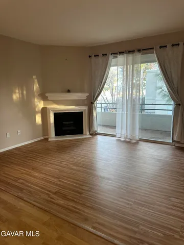 an empty room with wooden floor fireplace and windows