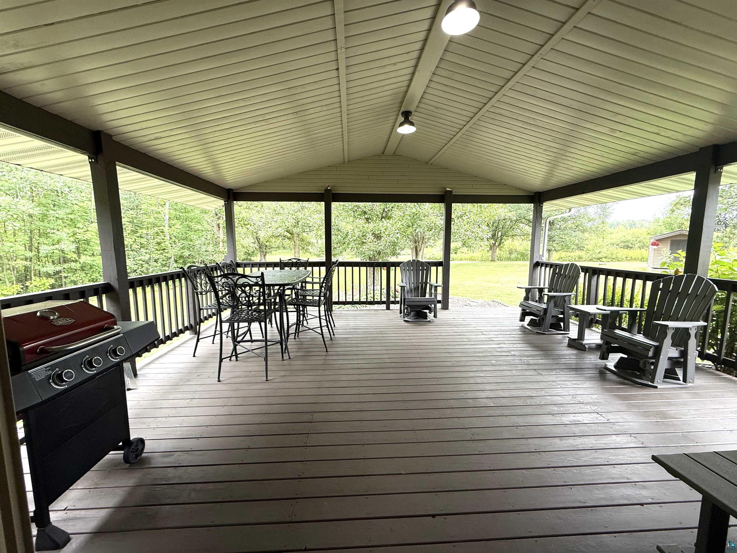5080 Tower Road Moose Lake, MN 55767 - Photo 31 of 49 Expansive covered porch featuring a planked floor, white paneled ceiling, dark railings, and ample outdoor living space