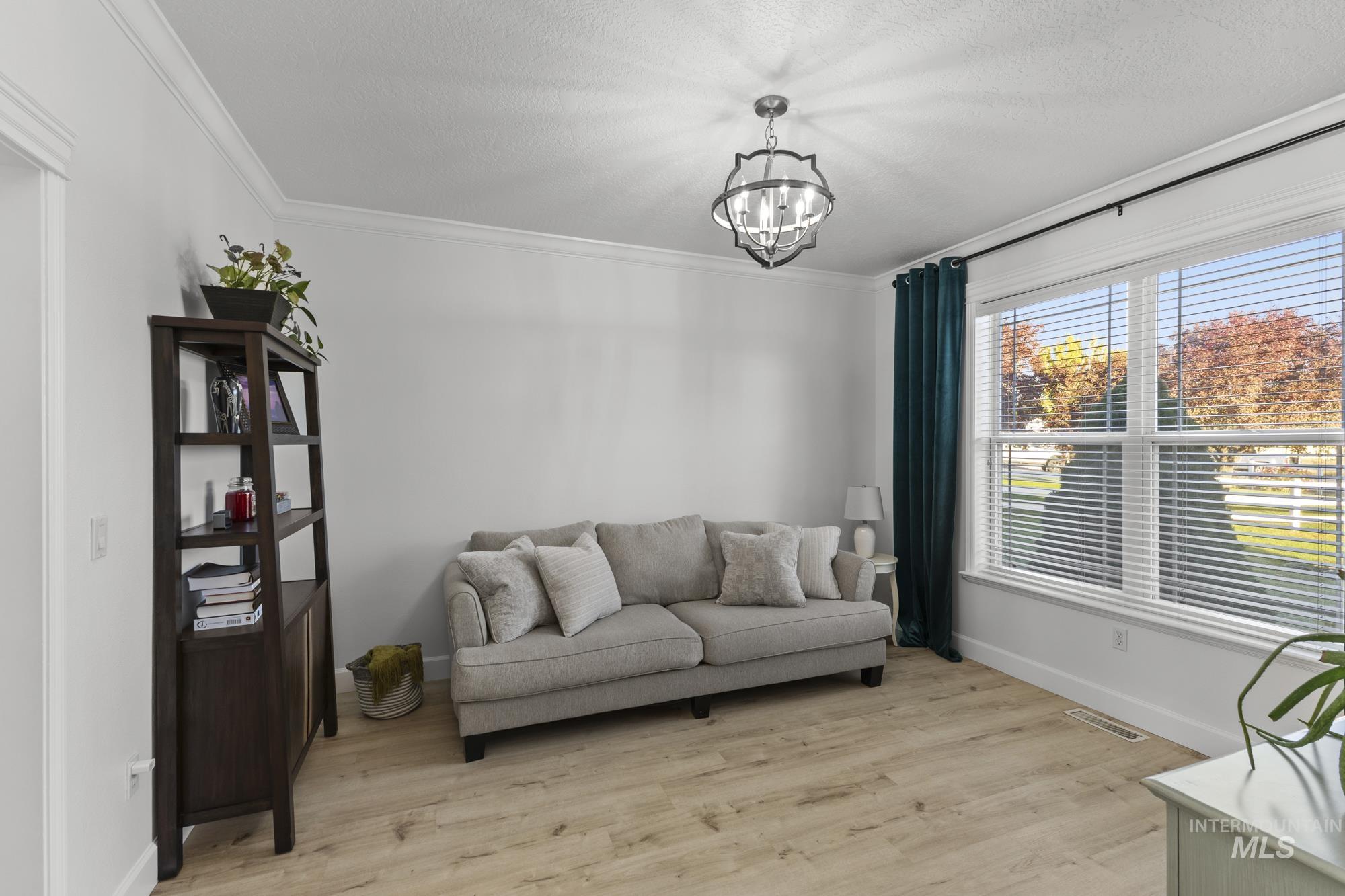 14820 Worden Way Caldwell, ID 83607 - Photo 12 of 44 Sitting room featuring light wood-type flooring, ornamental molding, hanging lights, and a textured ceiling