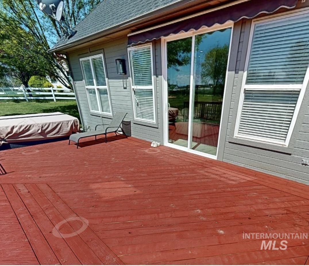 14820 Worden Way Caldwell, ID 83607 - Photo 42 of 44 Spacious red-stained wood deck featuring a covered spa, multiple windows with blinds, and a sliding glass door