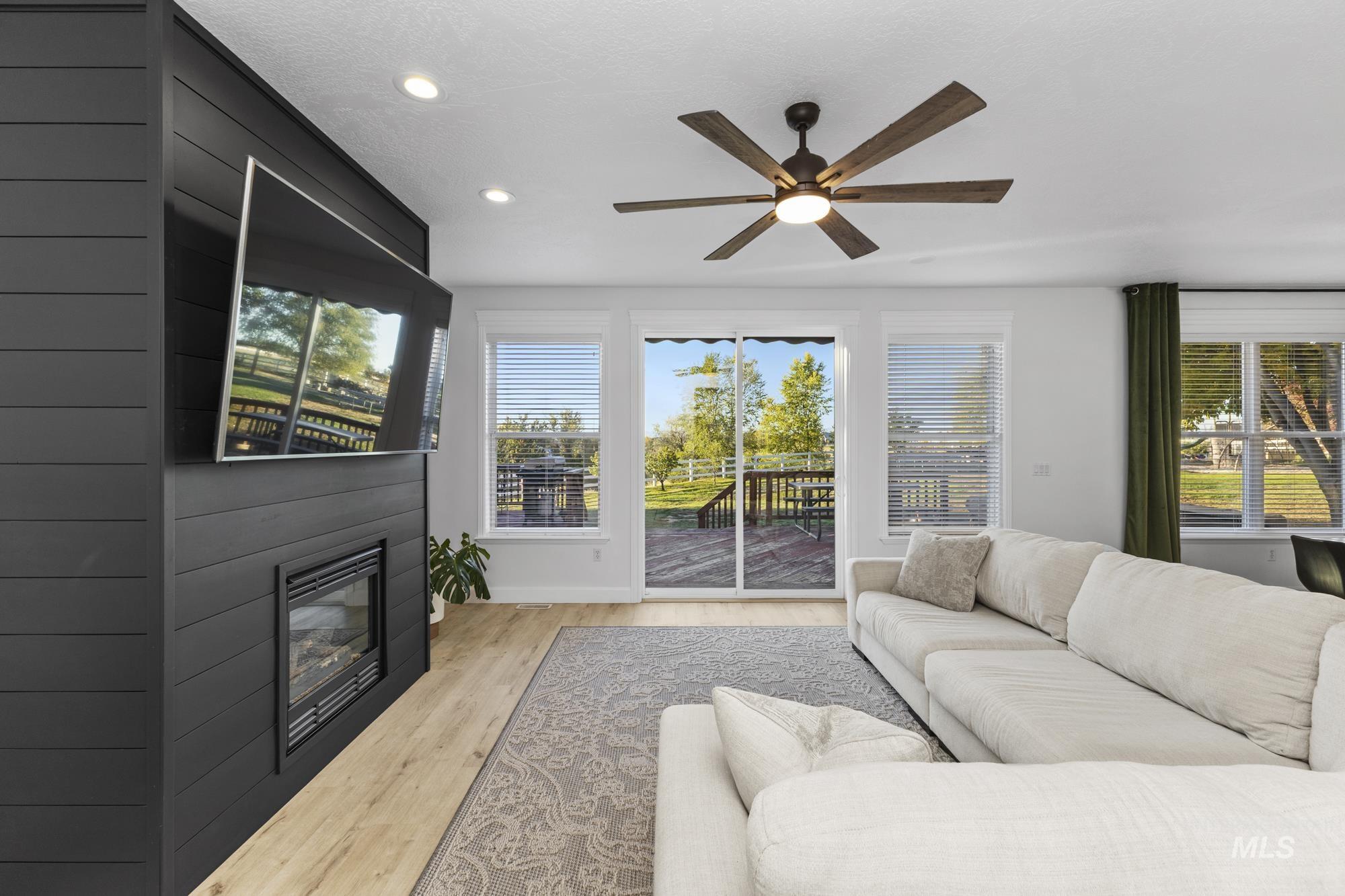 14820 Worden Way Caldwell, ID 83607 - Photo 5 of 44 Living area with light wood-style floors, healthy amount of natural light, recessed lighting, ceiling fan, and a glass covered fireplace