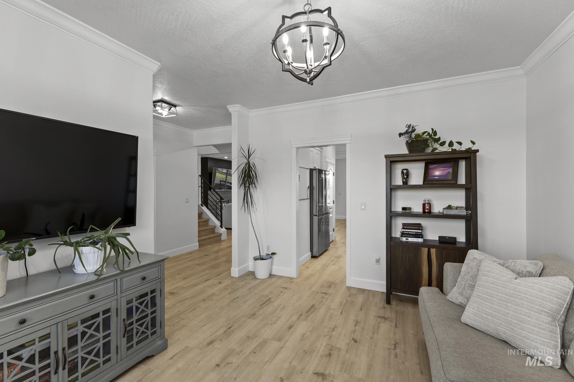 14820 Worden Way Caldwell, ID 83607 - Photo 10 of 44 Living room with light wood-style flooring, ornamental molding, a textured ceiling, and suspended lighting