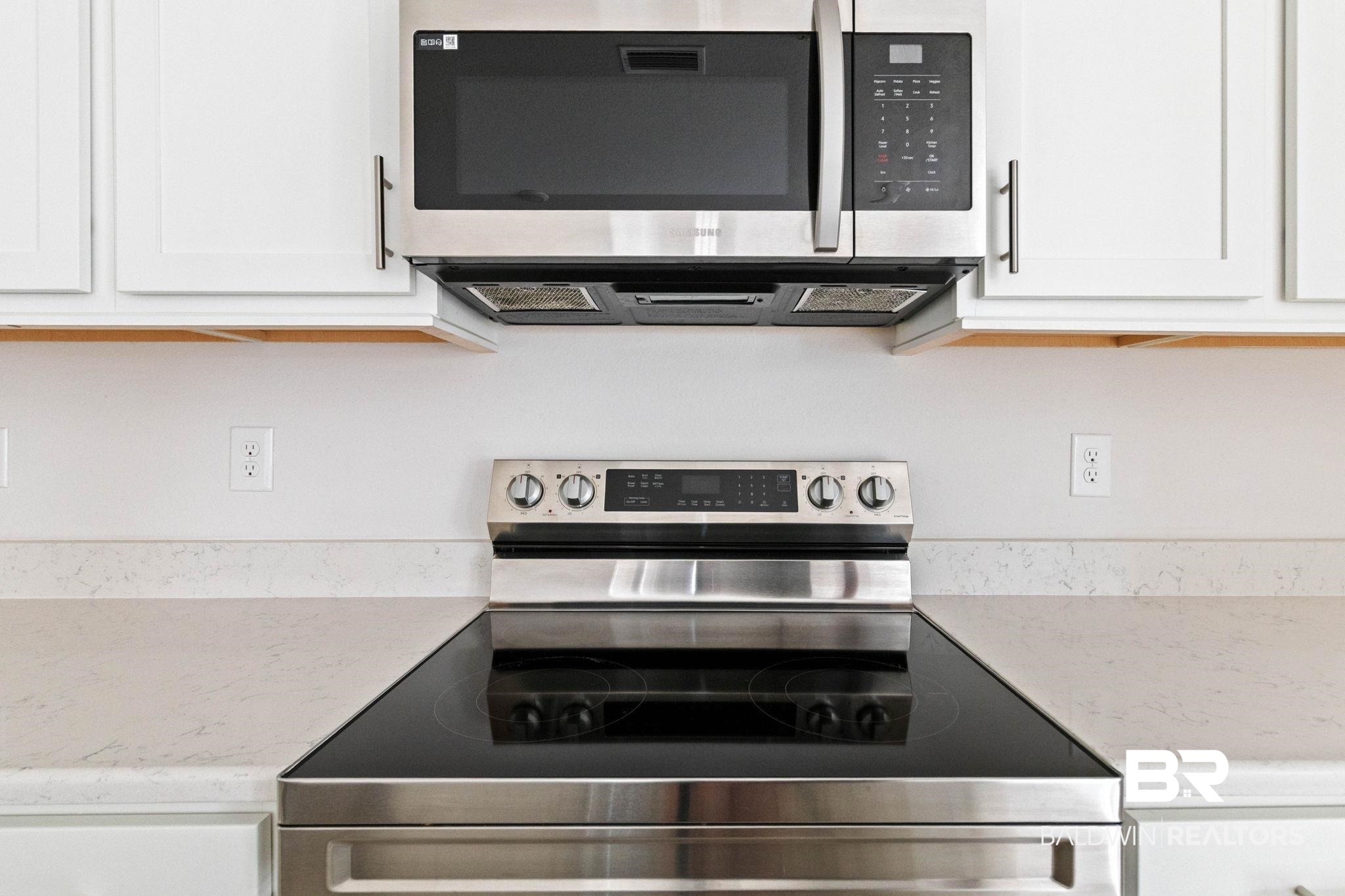 1710 Grouse Street Foley, AL 36535 - Photo 30 of 76 Modern kitchen featuring stainless steel appliances, including an electric range with a black glass cooktop and an over-the-range microwave