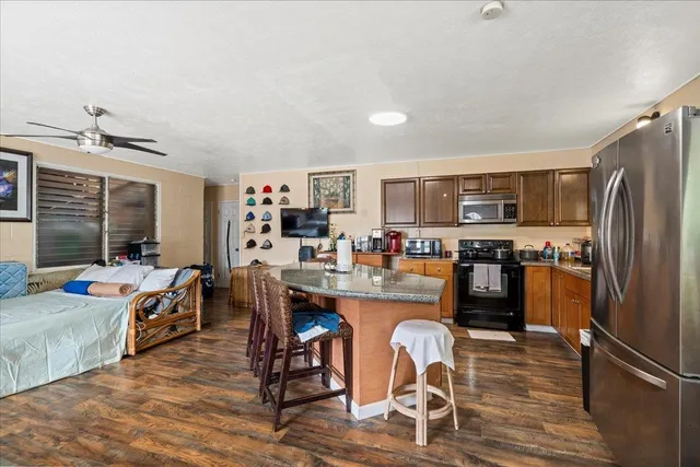 a kitchen with stainless steel appliances a dining table chairs stove refrigerator and cabinets