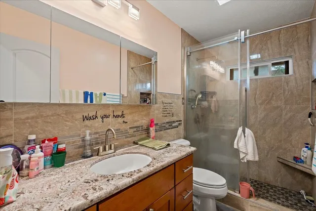 a bathroom with a granite countertop sink toilet and shower