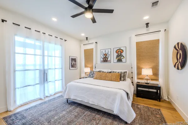 a bedroom with a bed painting on wall and a large window