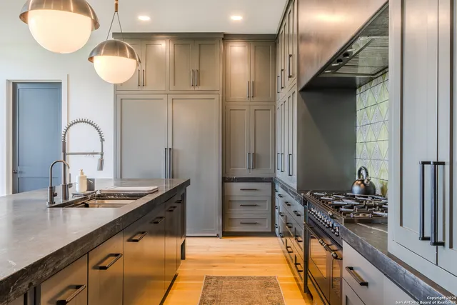 a kitchen with kitchen island granite countertop a sink stainless steel appliances and cabinets