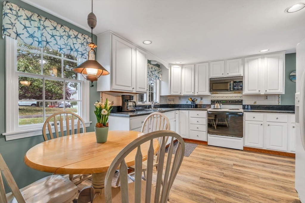 30 Cove Road Eastham, MA 02642 - Photo 13 of 42 a kitchen with stainless steel appliances granite countertop a stove a sink a microwave a dining table and chairs