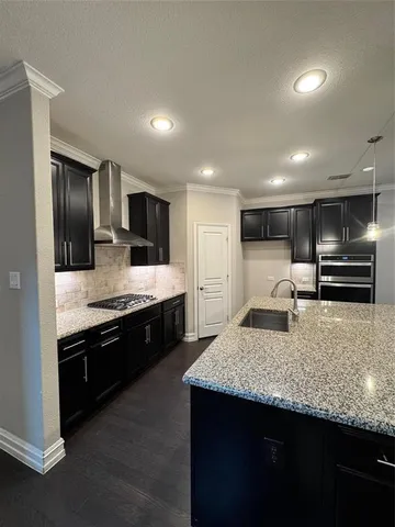 a large kitchen with stainless steel appliances kitchen island granite countertop a large counter top and stove top oven with wooden floor