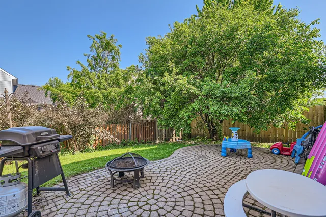 a view of a patio with a table and chairs potted plants and large tree