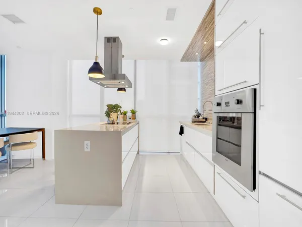 a kitchen with stainless steel appliances kitchen island granite countertop a stove a sink and white cabinets
