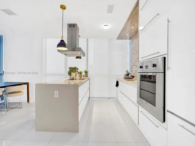a kitchen with stainless steel appliances kitchen island granite countertop a stove a sink and white cabinets