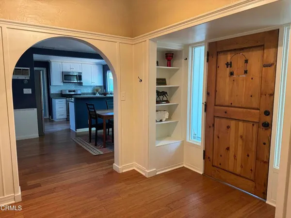 an empty room with wooden floor windows and entryway