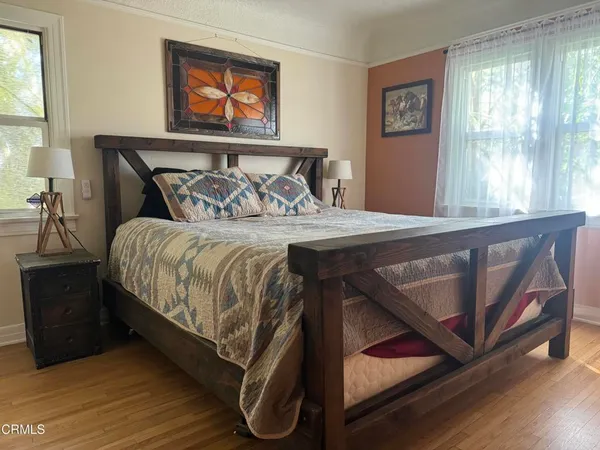 a bedroom with a bed a dresser with wooden floor