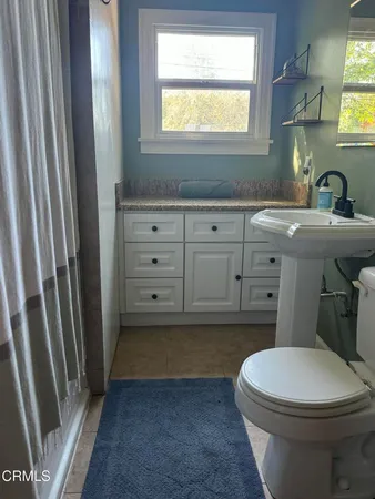 a bathroom with a sink a toilet a mirror and window