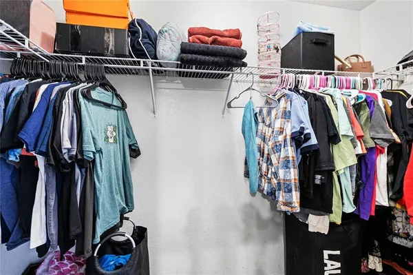 a view of walk in closet with clothes and shoes