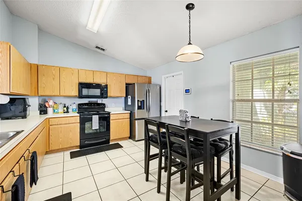 a kitchen with stainless steel appliances granite countertop a stove a sink dishwasher a dining table and chairs with wooden floor