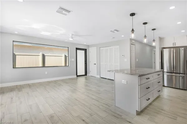 a view of kitchen and empty room with wooden floor
