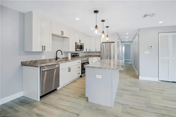 a kitchen with kitchen island a sink cabinets and wooden floor