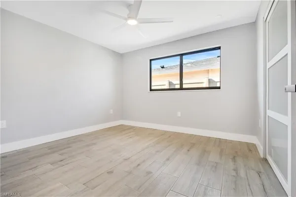 an empty room with wooden floor and windows
