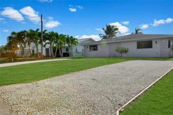 a front view of a house with a yard and potted plants