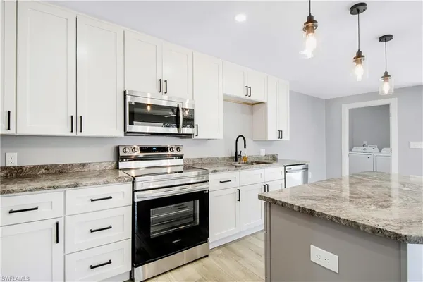 a kitchen with granite countertop a stove sink and cabinets
