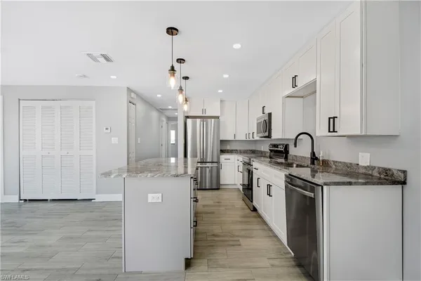a large kitchen with stainless steel appliances lots of counter space and wooden floor