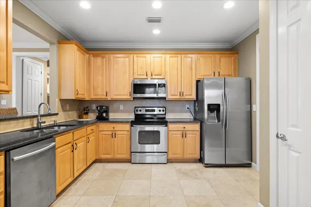a kitchen with stainless steel appliances granite countertop a refrigerator a sink dishwasher a stove and a microwave oven with cabinets