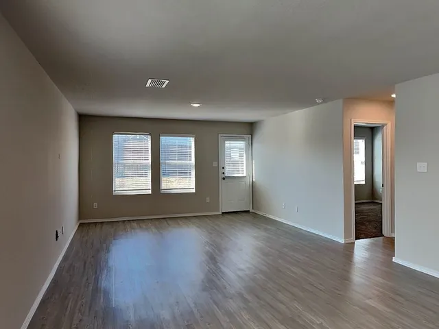 a view of empty room with wooden floor and window