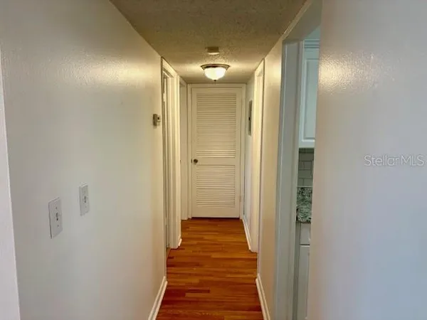 a view of a hallway with wooden floor and a bathroom
