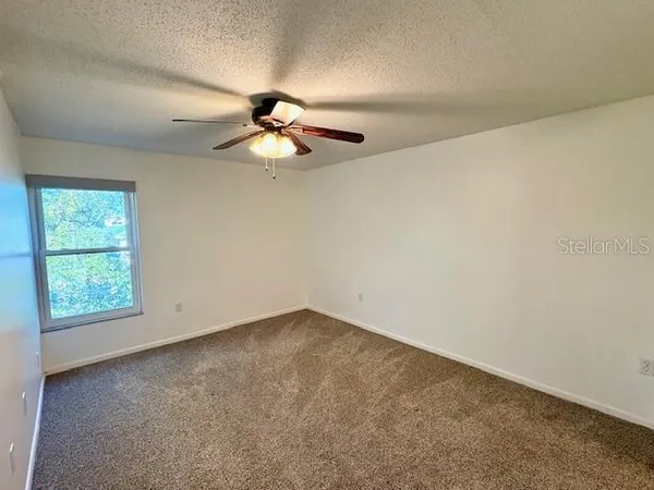 an empty room with a ceiling fan and closet area