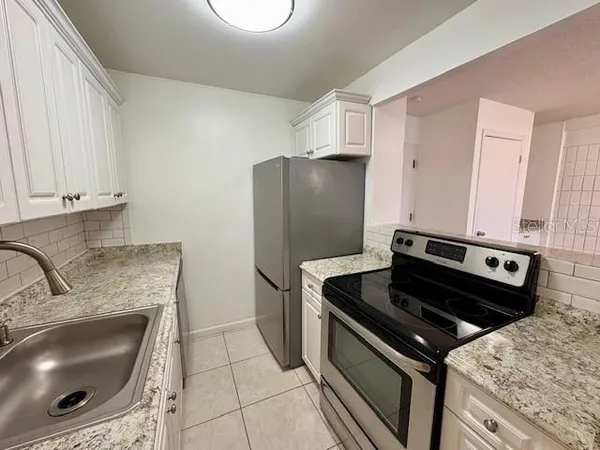 a kitchen with granite countertop a sink stove and refrigerator