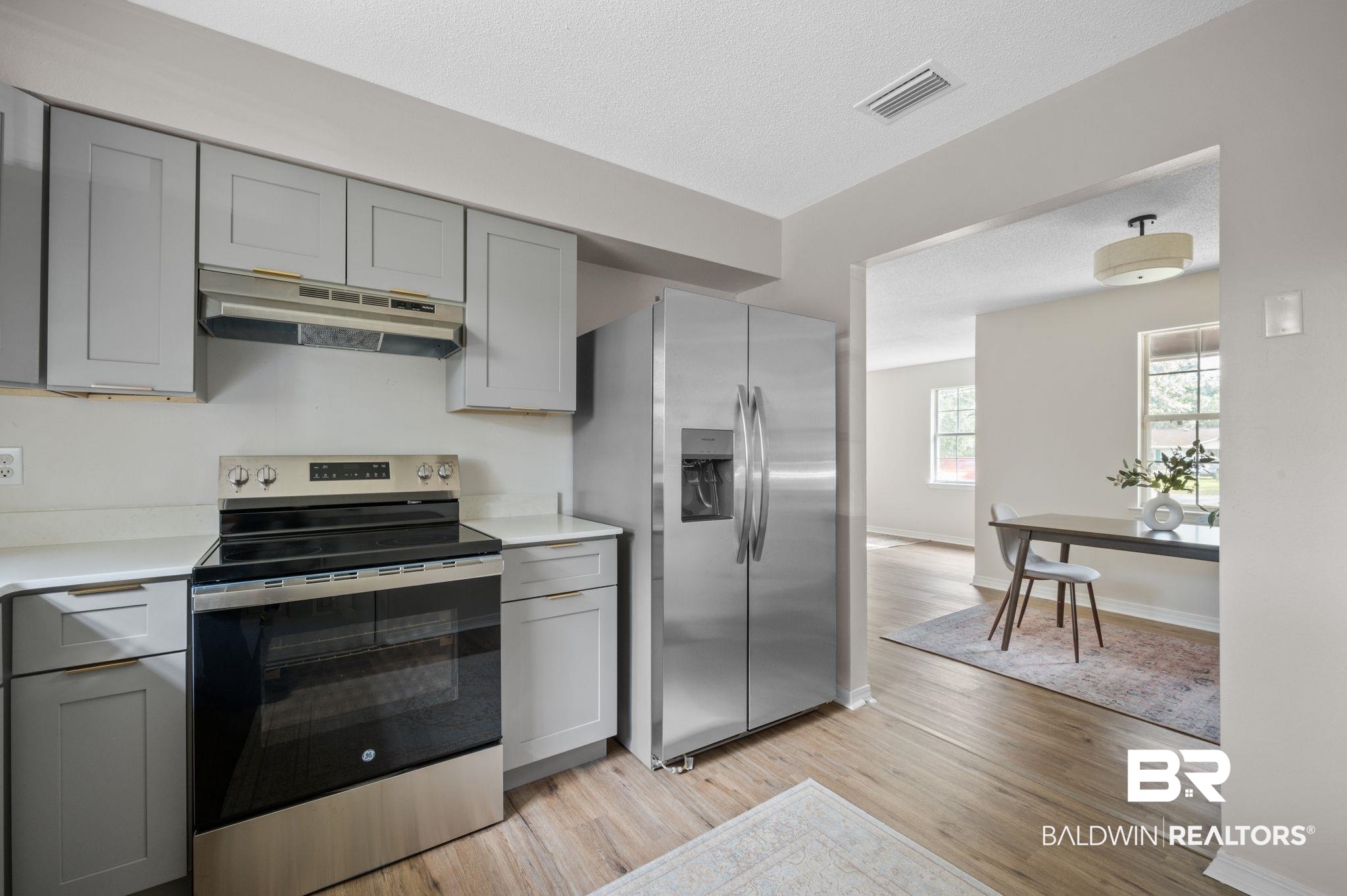 811 East Verbena Avenue Foley, AL 36535 - Photo 4 of 16 Kitchen featuring gray cabinetry, light wood-type flooring, stainless steel appliances, and a textured ceiling