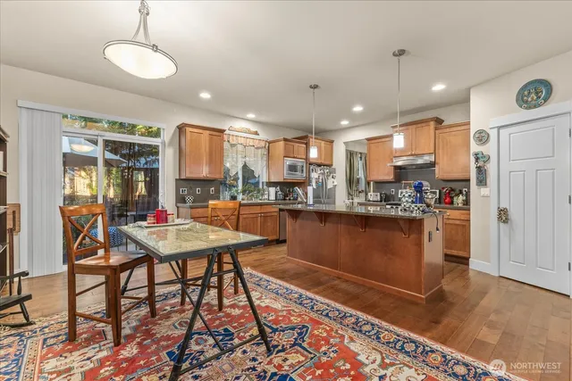 a kitchen with stainless steel appliances granite countertop wooden cabinets a dining table and chairs