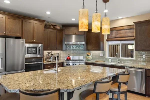 a kitchen with kitchen island granite countertop a stove a sink a refrigerator and wooden cabinets