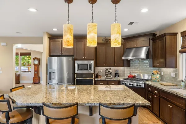 a kitchen with kitchen island a stove a sink a counter top space and living room view