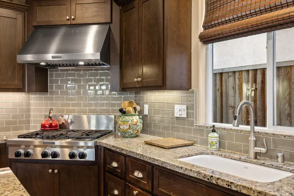 a kitchen with granite countertop a stove top oven cabinetry a sink and a window