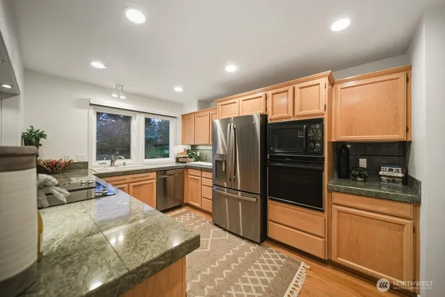 a kitchen with stainless steel appliances granite countertop a refrigerator and a sink