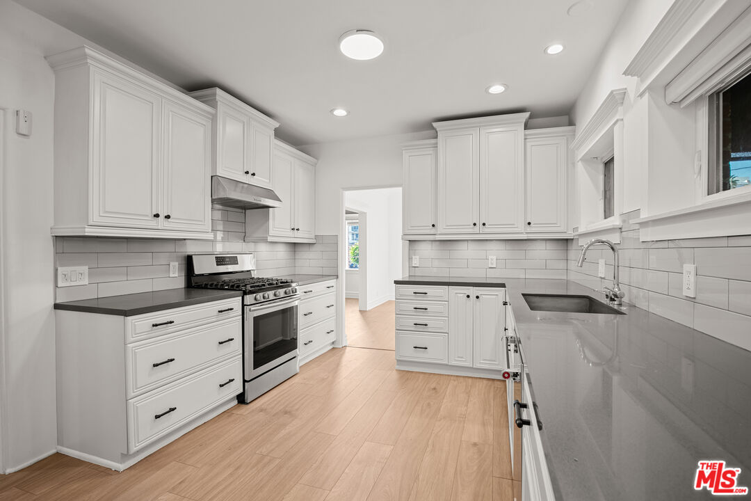 8467 West 4th Street Los Angeles, CA 90048 - Photo 2 of 12 a kitchen with granite countertop white cabinets and white stainless steel appliances