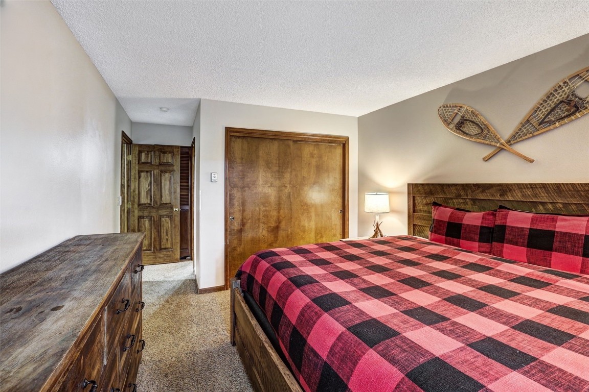 840 4 O Clock Road, Unit A1D Breckenridge, CO 80424 - Photo 17 of 38 a bedroom with a bed and a dresser with rug