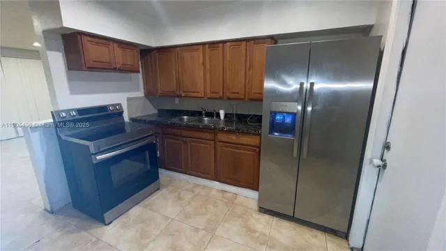 a kitchen with stainless steel appliances granite countertop a stove a refrigerator and a sink