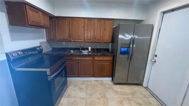 a kitchen with stainless steel appliances granite countertop a refrigerator a sink and wooden cabinets